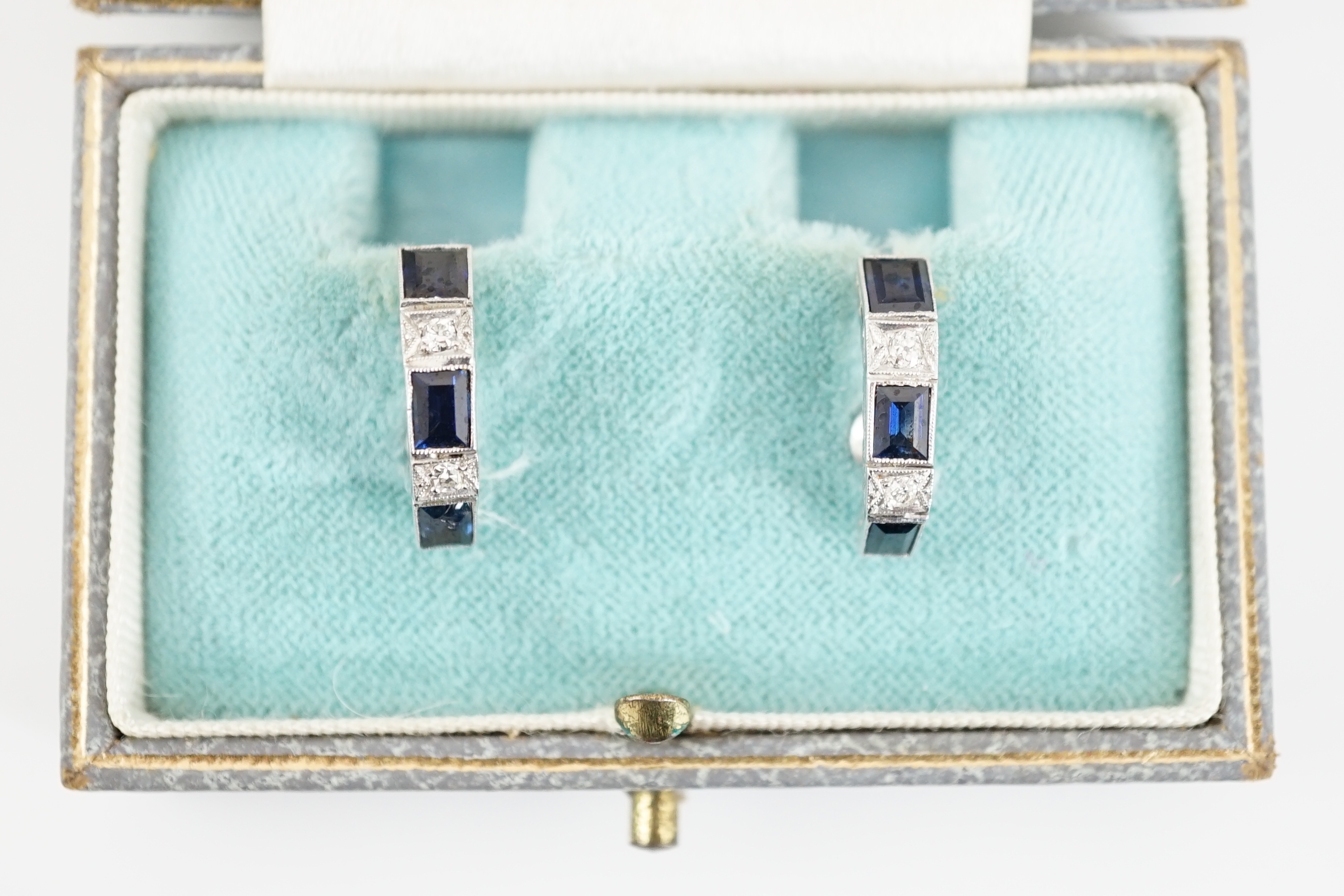 A pair of 9ct white gold, three stone sapphire and two stone diamond set half hoop ear clips, 16mm, gross weight 4.1 grams.